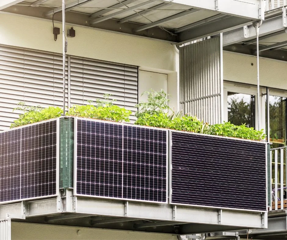 Balkonsolarkraftwerk am Balkongeländer neben Pflanzen
