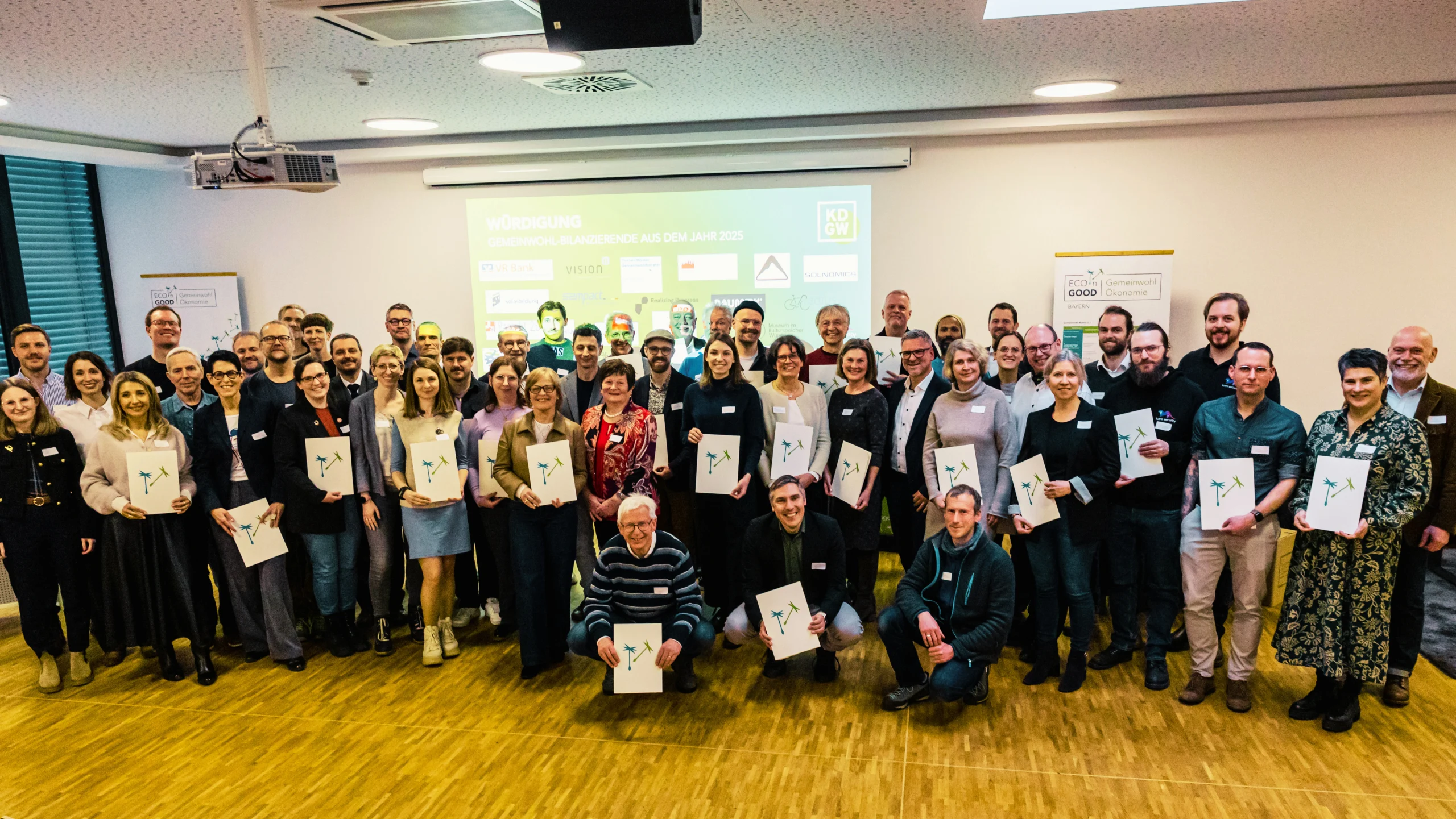 Große Gruppe von Menschen mit Urkunden im Saal, Gruppenfoto