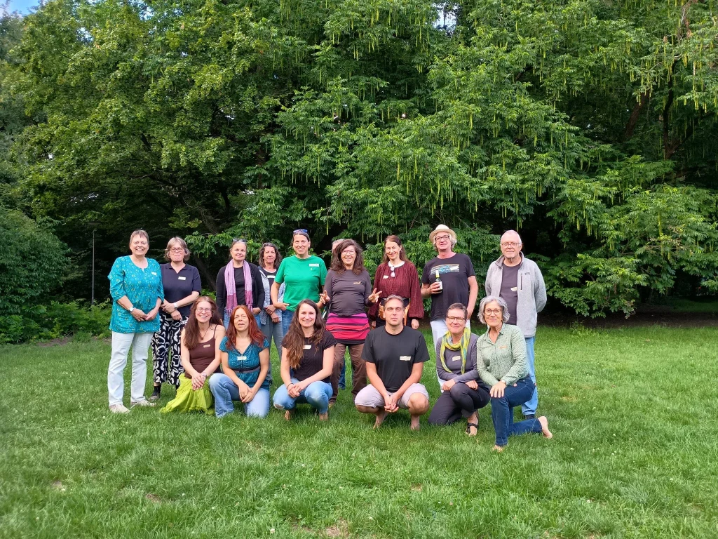 Gruppenfoto von Menschen auf einer Wiese unter Bäumen