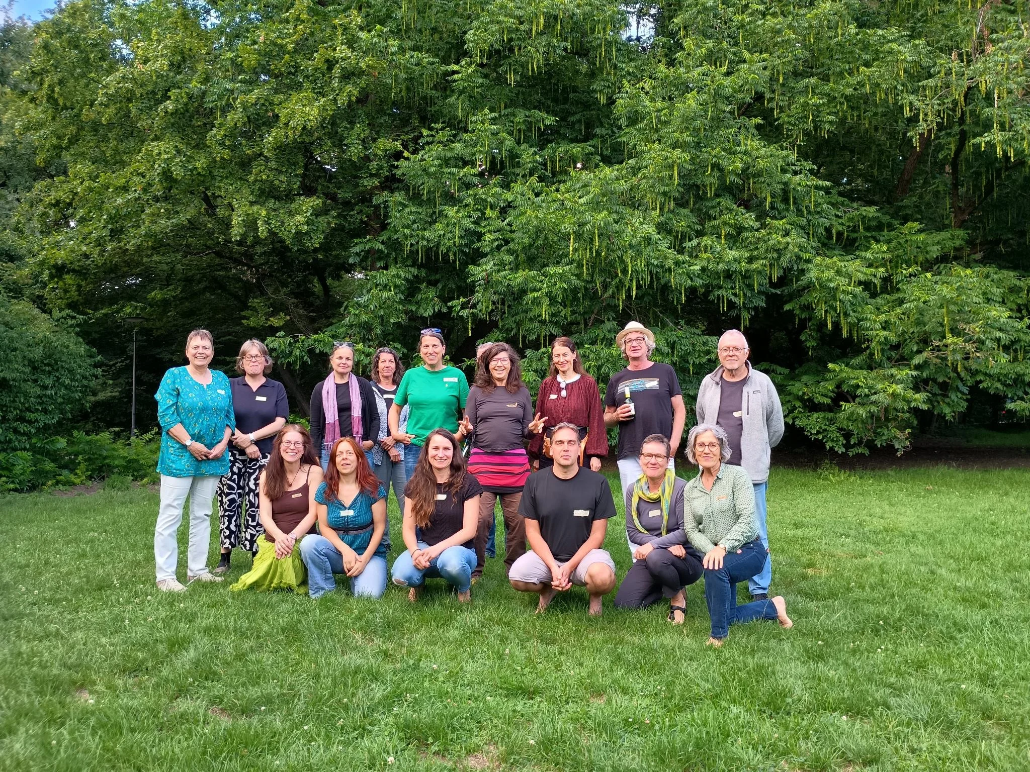 Gruppenfoto von Menschen auf einer Wiese unter Bäumen
