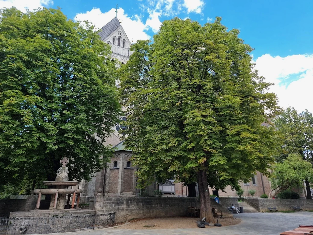 Kirchenbau mit Turm zwischen Bäumen im Lehel