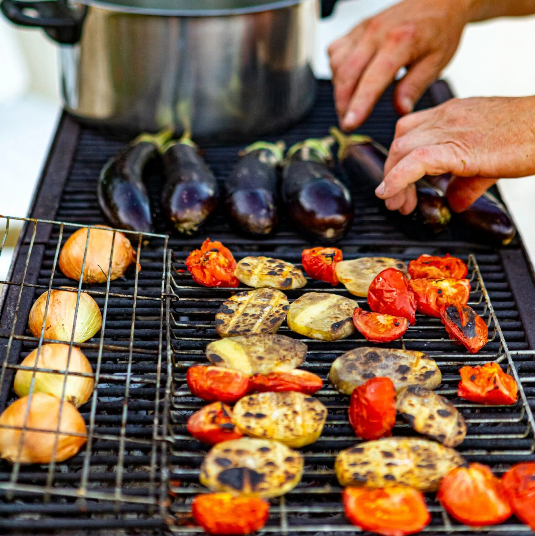 Gemüse brutzelt auf einem Grill, eine Hand wendet es