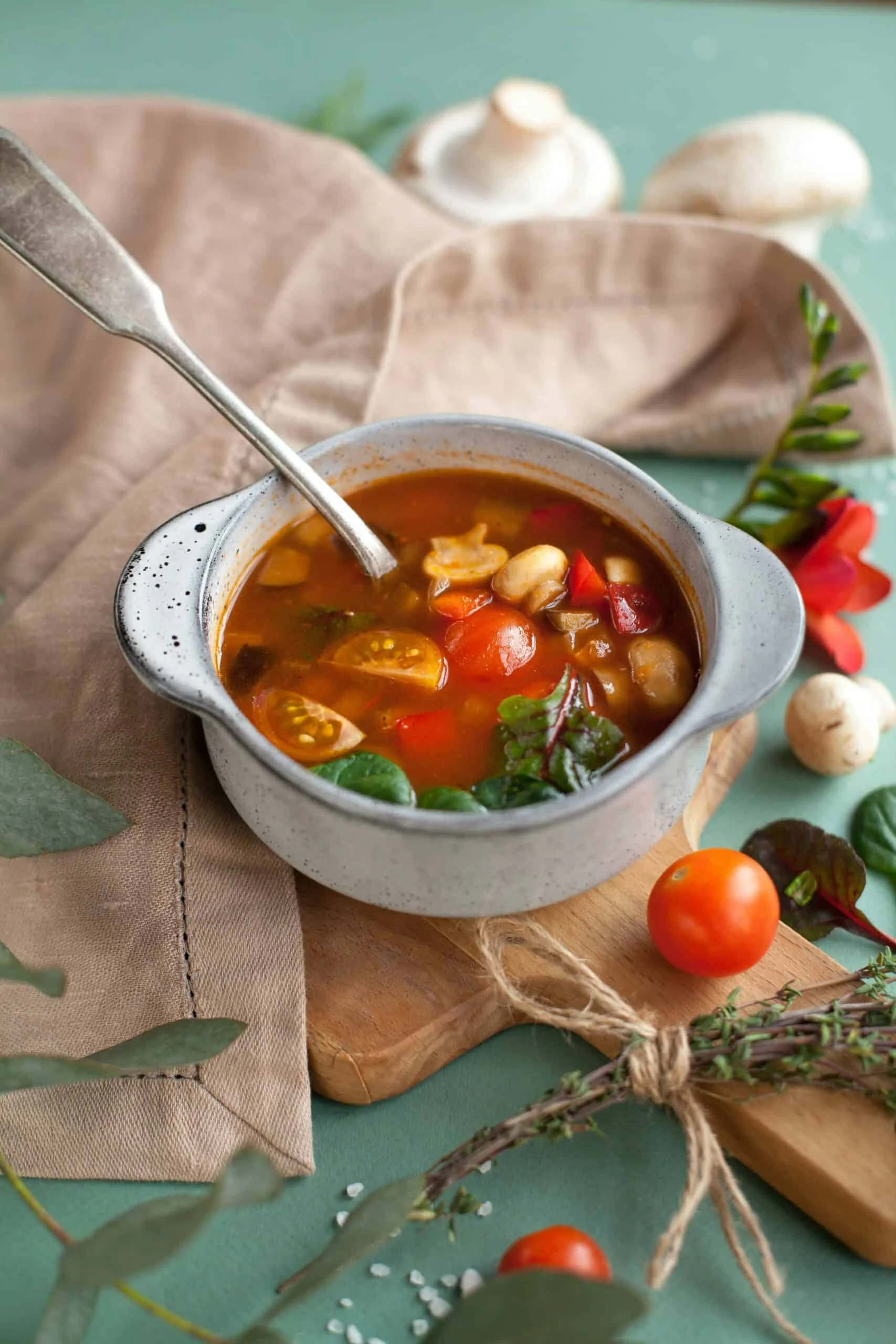 Schüssel mit Gemüsesuppe auf einem Tisch neben frischen Tomaten